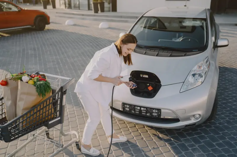 Mujer con la compra y coche eléctrico en supermercado