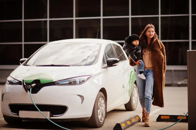 Mujer niño cargando vehículo eléctrico