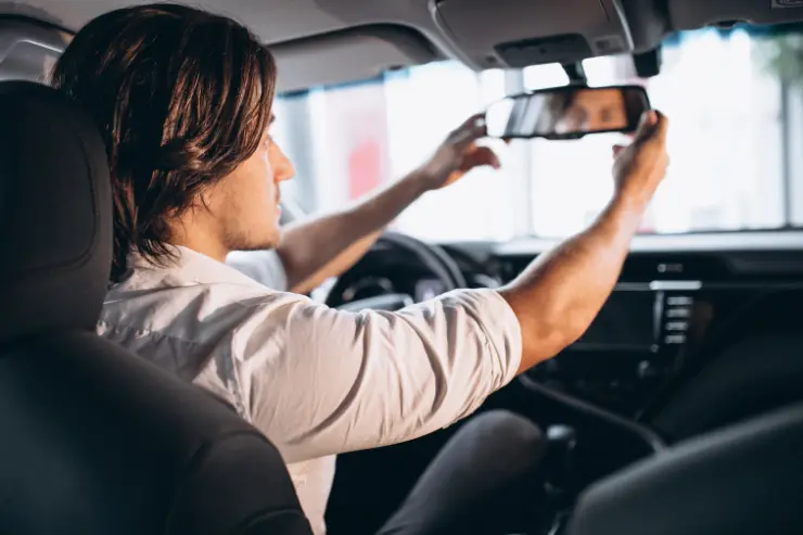 Hombre colocando el espejo en su coche de lujo